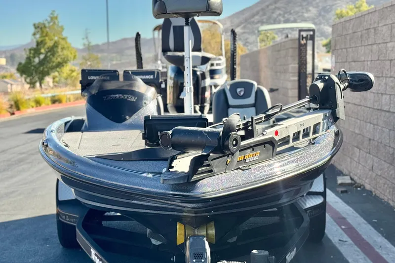 Slide: The Image of 2018 Triton 19 TrX Patriot boat with advanced fishing equipment, parked outdoors. - 2