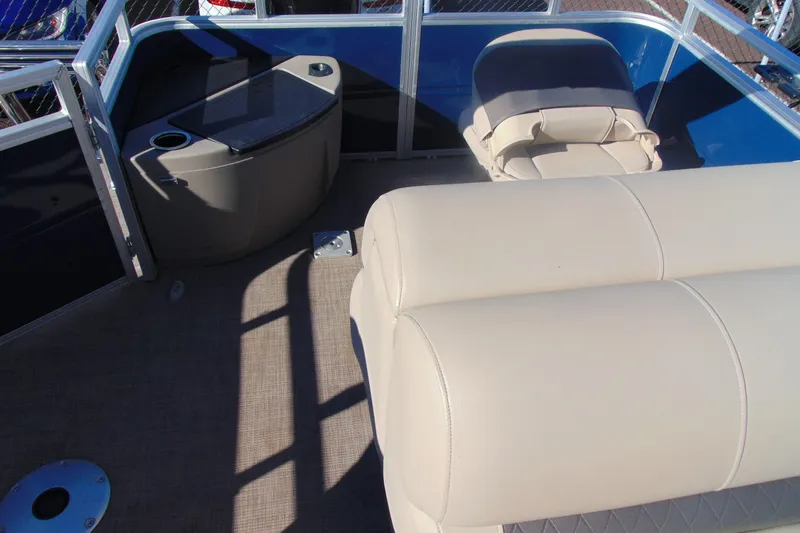 Slide: The Image of 2024 Sun Tracker Fishin' Barge 20 DLX interior with beige seating and storage area. - 12