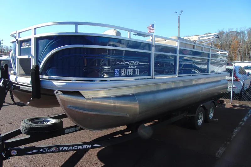 Slide: The Image of 2024 Sun Tracker Fishin' Barge 20 DLX pontoon boat on trailer, parked outdoors. - 5