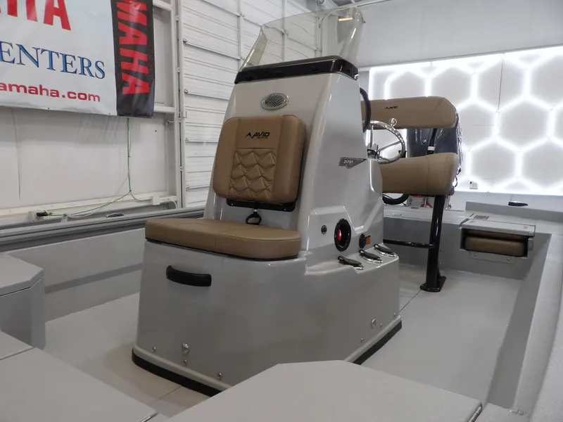 Slide: The Image of 2026 Avid 21FST boat interior with tan seating and steering console in showroom. - 11