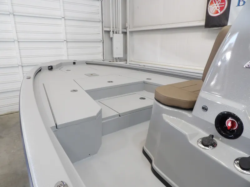 Slide: The Image of 2026 Avid 21FST boat interior with gray deck and tan seating in a garage setting. - 12