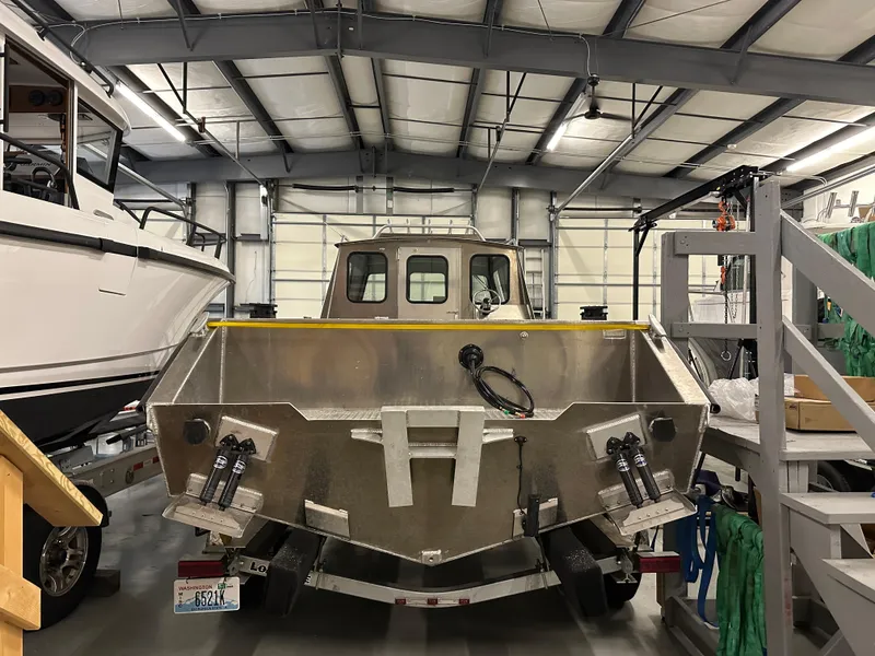 Slide: The Image of Northshore 24 boat, 2025 model, in a warehouse with metal framework and equipment. - 10