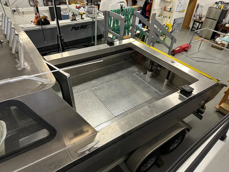 Slide: The Image of Northshore 24 boat, 2025 model, in a workshop setting, showcasing its aluminum deck and trailer. - 14