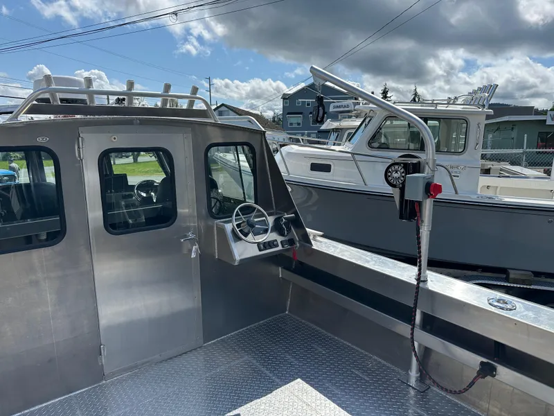 Slide: The Image of 2025 Northshore 24 boat with metal cabin and steering wheel, docked under cloudy sky. - 17