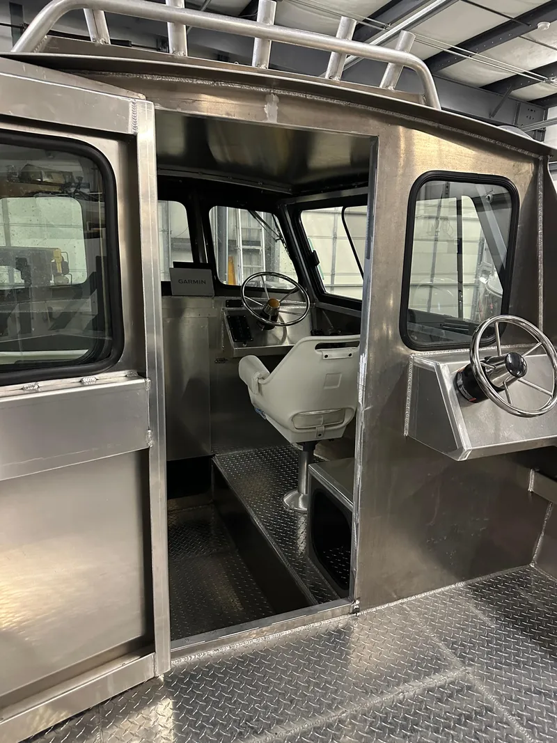 Slide: The Image of 2025 Northshore 24 boat interior with steering wheel and seating in a metal cabin. - 7