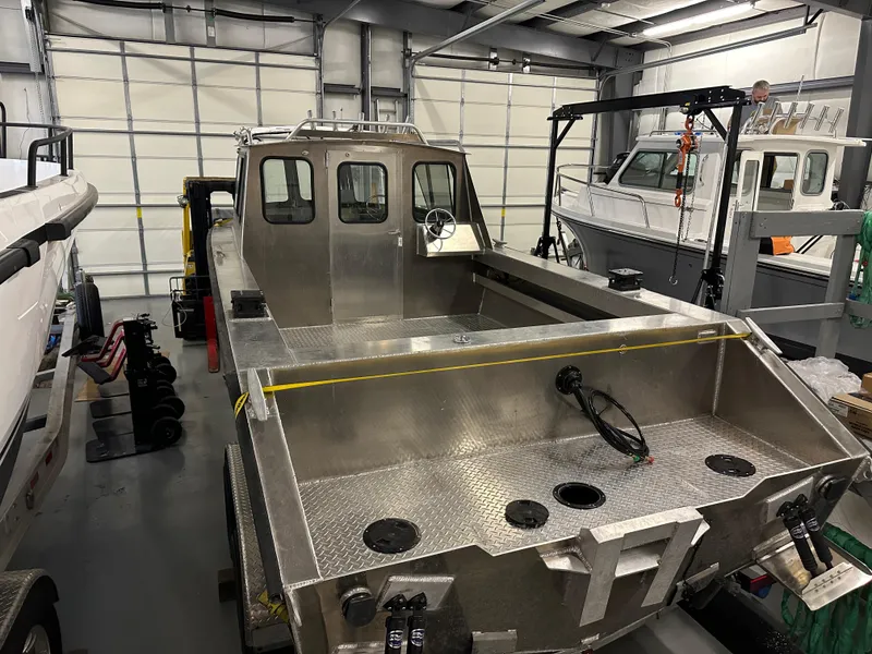 Slide: The Image of 2025 Northshore 24 boat in a garage, showcasing its sturdy aluminum build and spacious deck. - 9