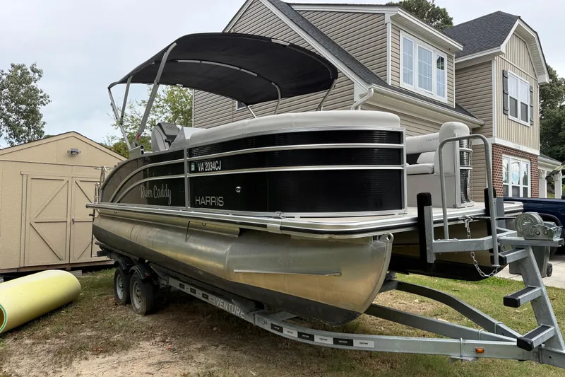 Slide: The Image of 2021 Harris Cruiser 210 pontoon boat on trailer beside house and shed. - 3
