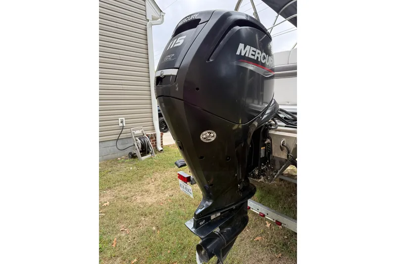 Slide: The Image of 2021 Harris Cruiser 210 with Mercury outboard motor, parked beside a house. - 5