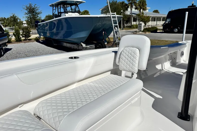 Slide: The Image of 2026 Caymas 28 HB boat interior with white quilted seating, parked outdoors. - 18
