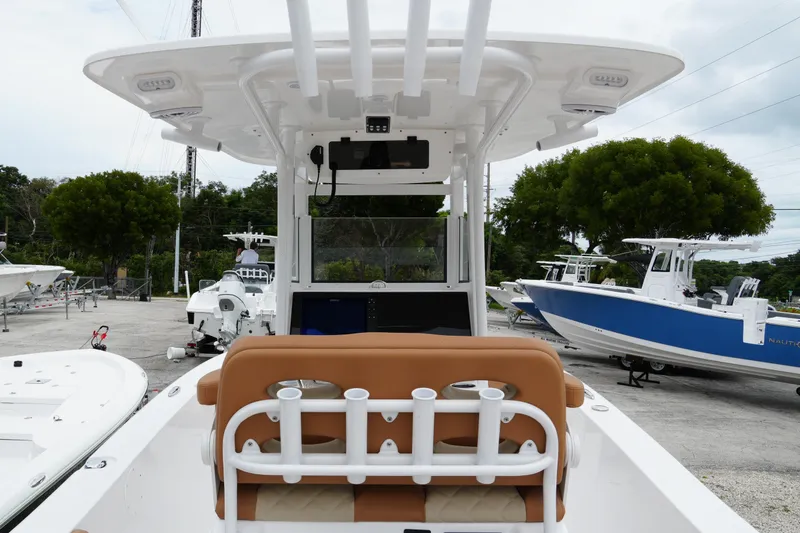 Slide: The Image of 2025 NauticStar 252 Legacy boat interior with helm and rod holders, docked outdoors. - 13