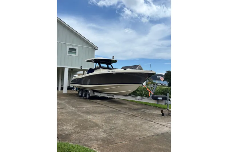 Slide: The Image of 2018 Chris-Craft 350 Catalina boat on trailer, parked beside a house under a clear sky. - 2