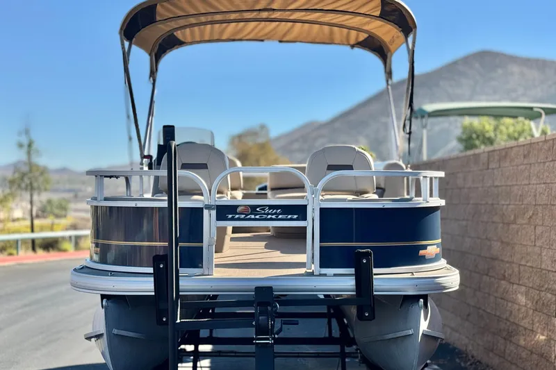 Slide: The Image of 2023 Sun Tracker Bass Buggy 18 DLX pontoon boat with canopy, parked on trailer. - 2