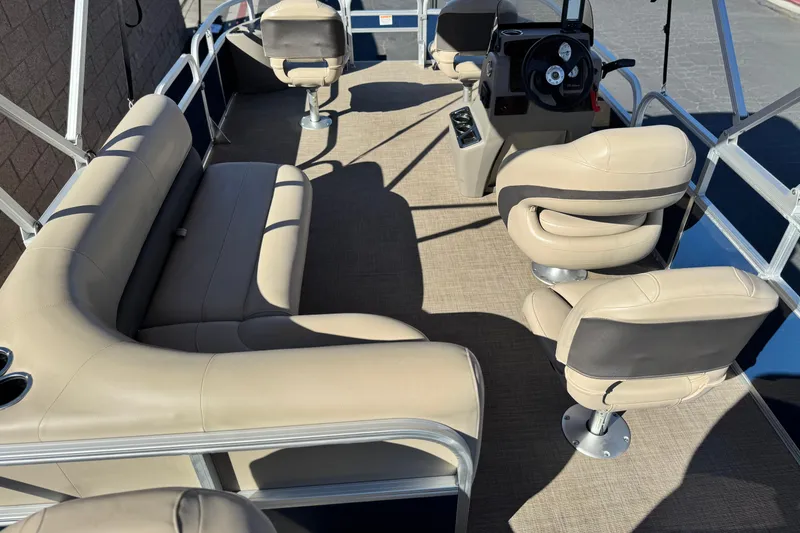 Slide: The Image of 2023 Sun Tracker Bass Buggy 18 DLX pontoon boat interior with beige seating and steering console. - 22