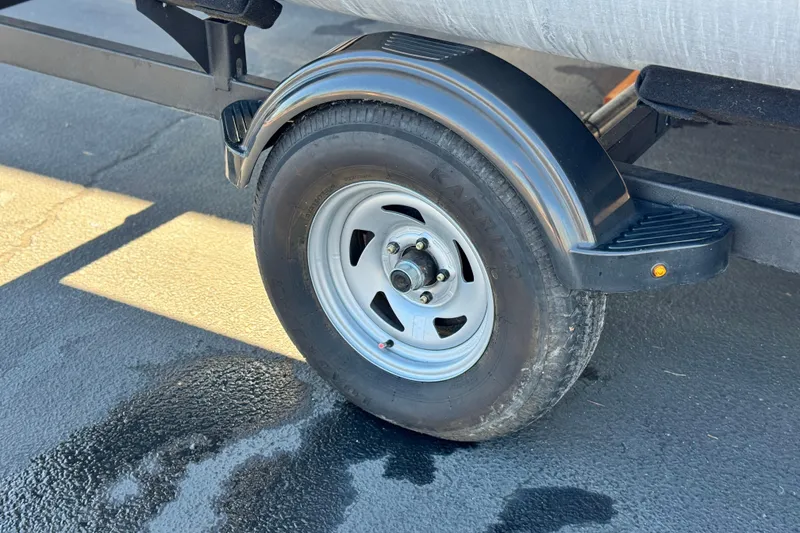 Slide: The Image of Trailer wheel of 2023 Sun Tracker Bass Buggy 18 DLX on wet pavement. - 27