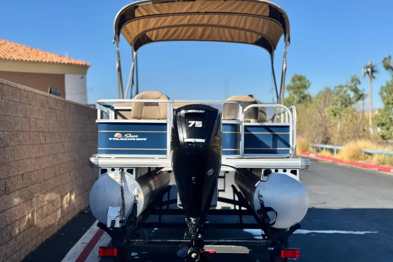 Slide: The Image of 2023 Sun Tracker Bass Buggy 18 DLX pontoon boat with Mercury 75 engine, parked outdoors. - 5