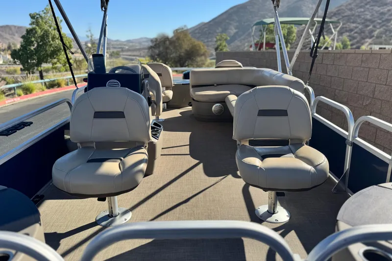 Slide: The Image of 2023 Sun Tracker Bass Buggy 18 DLX pontoon boat interior with seating and scenic background. - 9