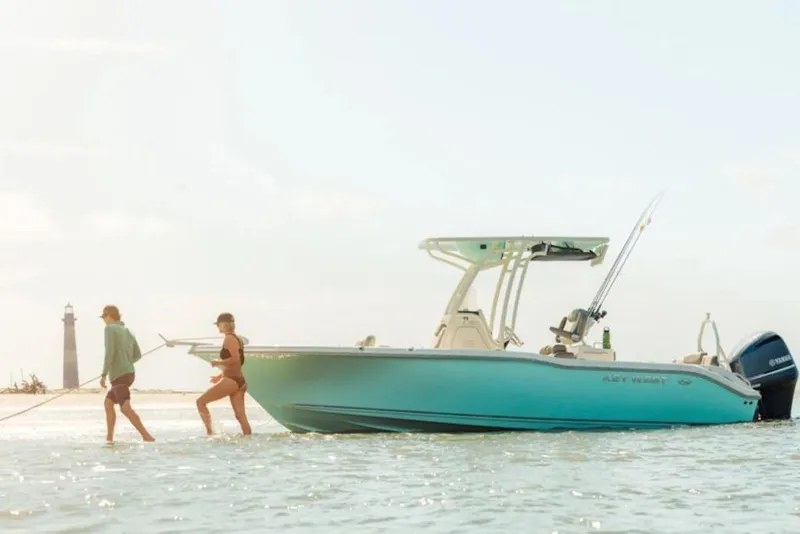 The Image of 2026 Key West 239 FS boat in shallow water with two people nearby. - 1