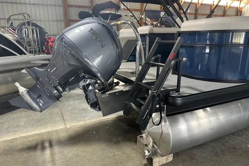 Slide: The Image of 2026 Godfrey Xperience 2286 SBX pontoon boat with Yamaha outboard motor in a storage facility. - 2