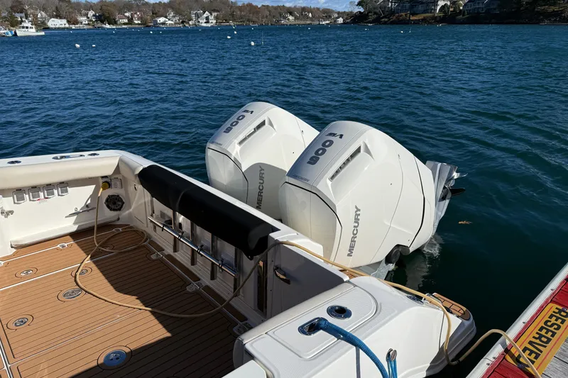 Slide: The Image of 2024 Boston Whaler 380 Realm with dual Mercury 600 engines on a calm lake. - 2