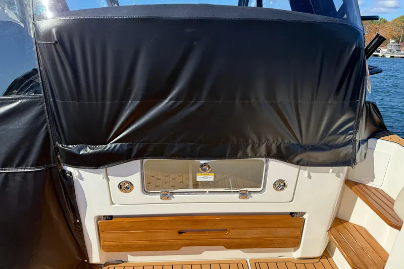 Slide: The Image of 2024 Boston Whaler 380 Realm boat interior with black cover and wooden accents. - 4