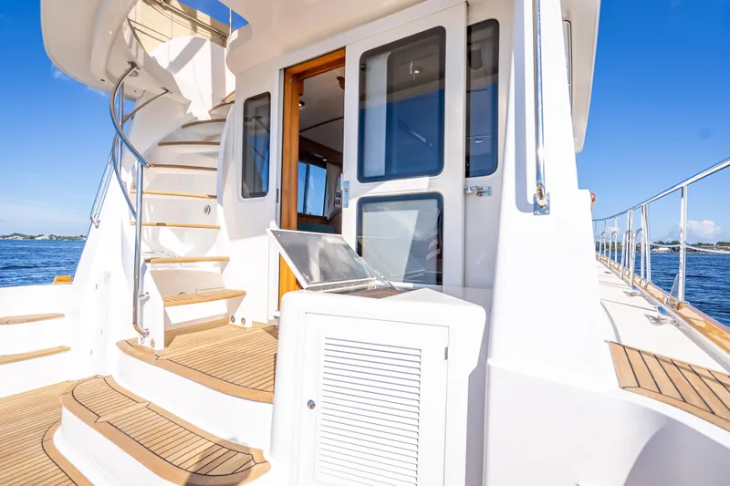 Slide: The Image of 2008 Grand Banks 47 Eastbay FB yacht with spiral staircase and open door, on calm water. - 14