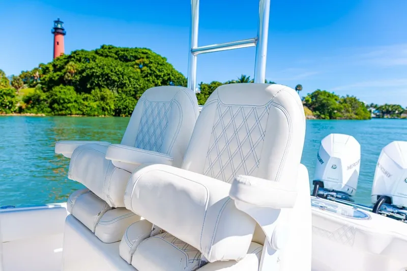 Slide: The Image of 2022 Conch 27 boat with white seats, lighthouse, and lush greenery in the background. - 26