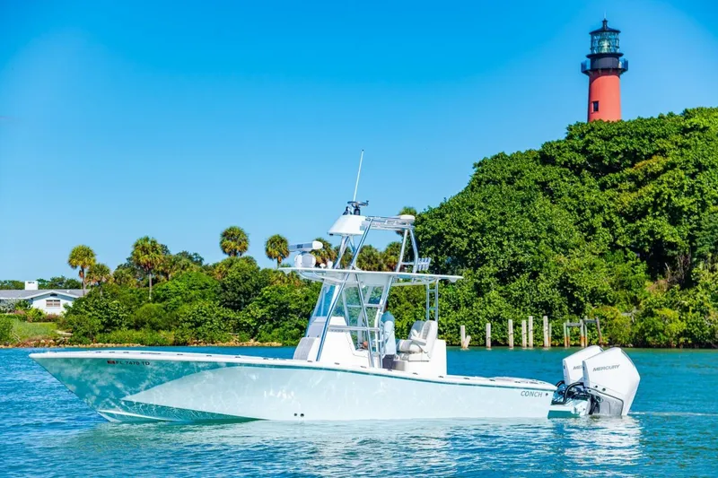 Slide: The Image of 2022 Conch 27 boat on water near lush greenery and lighthouse. - 5
