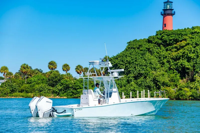 Slide: The Image of 2022 Conch 27 boat cruising near a lighthouse with lush greenery. - 9