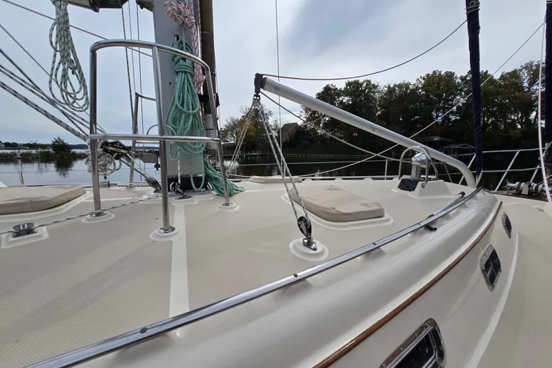 Slide: The Image of 2001 Island Packet 420 sailboat deck with rigging and ropes, docked by a calm river. - 8