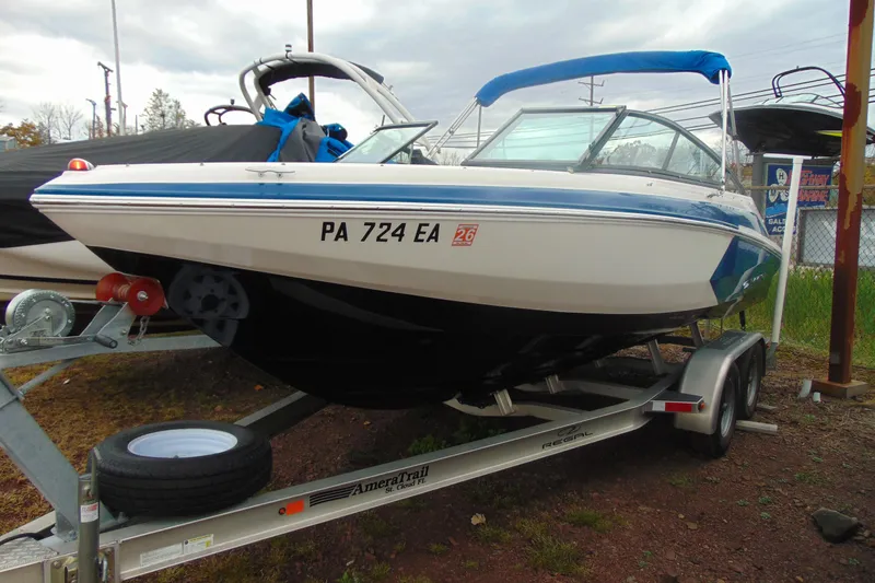 The Image of 2016 Regal 2000 ESX Bowrider on trailer, blue and white design, parked outdoors. - 0