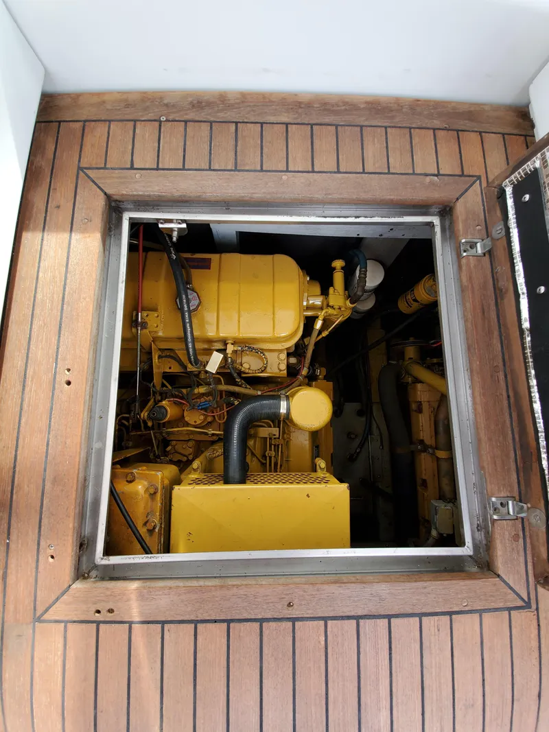 Slide: The Image of Engine compartment of a 1993 Giorgi 46 boat, featuring a yellow engine, viewed through a wooden hatch. - 32