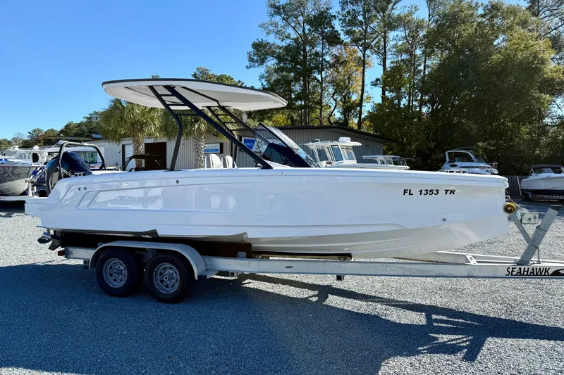 Slide: The Image of 2022 Axopar 22 boat on trailer, parked outdoors, surrounded by trees and other boats. - 10