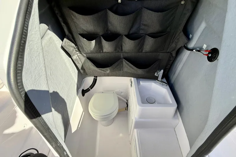Slide: The Image of Compact bathroom in 2022 Axopar 22 boat with toilet, sink, and storage pockets. - 32