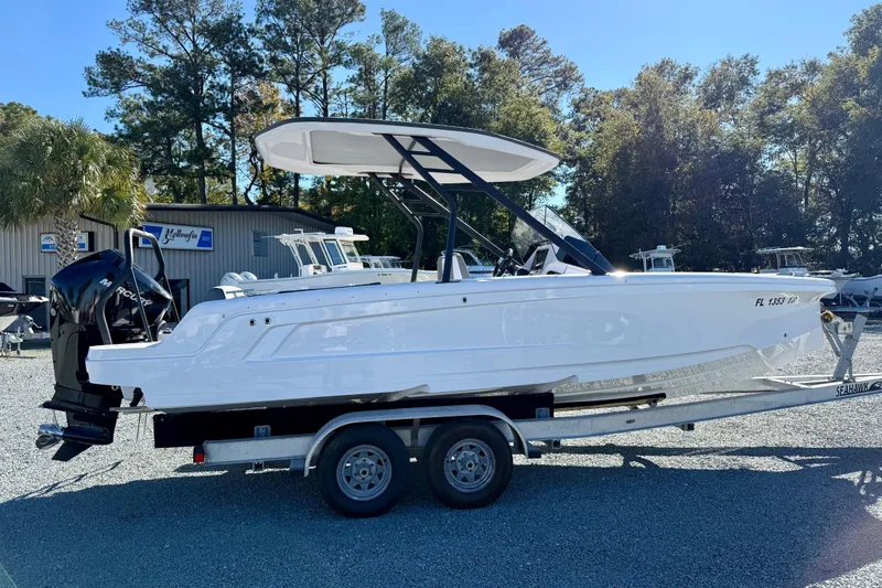 Slide: The Image of 2022 Axopar 22 boat on trailer, parked outdoors with trees in background. - 9