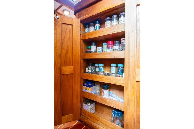 Slide: The Image of Wooden spice cabinet on 1984 Hank Hinckley OC42 boat, filled with various jars and containers. - 28