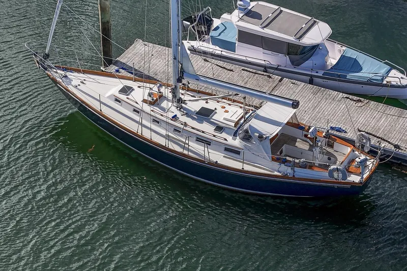 Slide: The Image of 1984 Hank Hinckley OC42 sailboat docked beside a motorboat on calm water. - 4