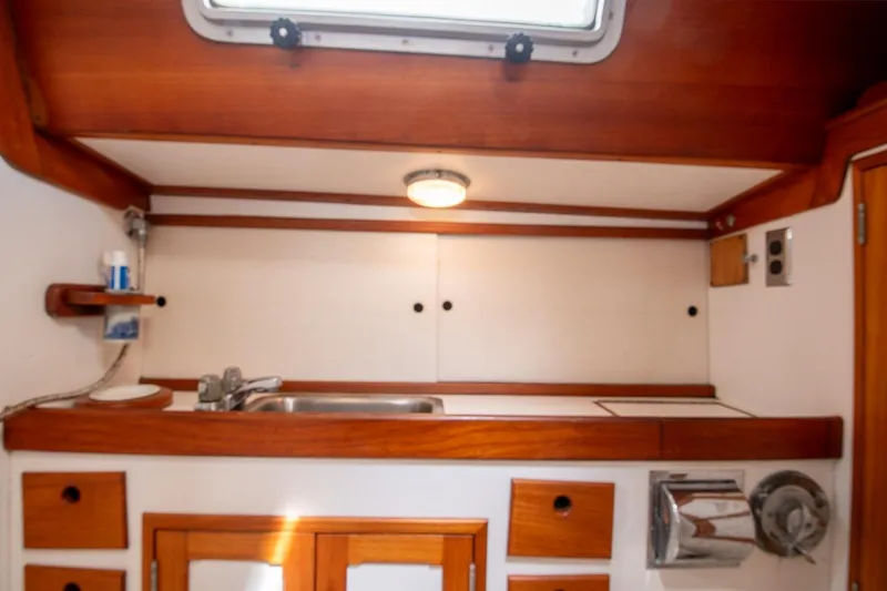 Slide: The Image of Compact galley kitchen in 1984 Hank Hinckley OC42 sailboat with wooden cabinetry and stainless steel sink. - 50