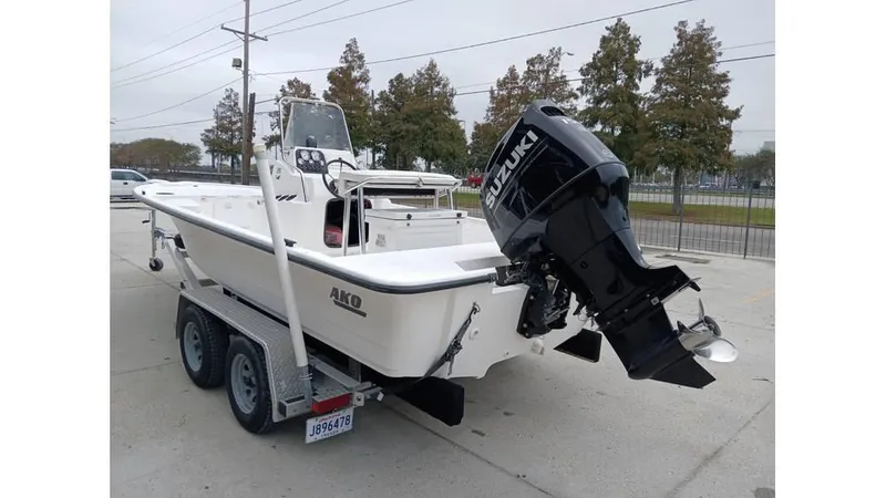 Slide: The Image of 2006 Mako 211 boat on trailer with Suzuki outboard motor, parked outdoors. - 10