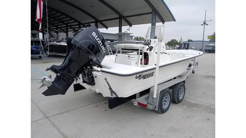 Slide: The Image of 2006 Mako 211 boat on trailer with Suzuki outboard motor, parked outdoors. - 11