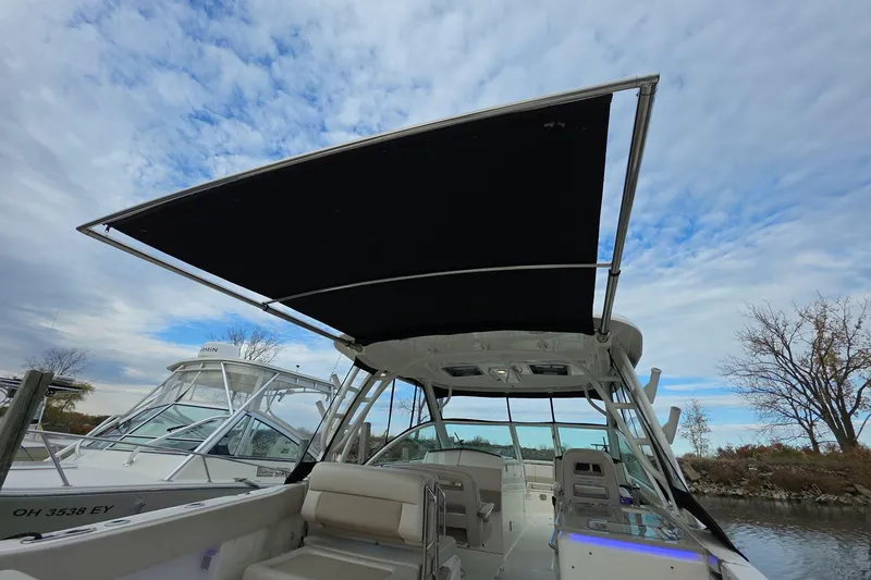 Slide: The Image of 2018 Boston Whaler 320 Vantage boat with canopy, docked under a cloudy sky. - 17