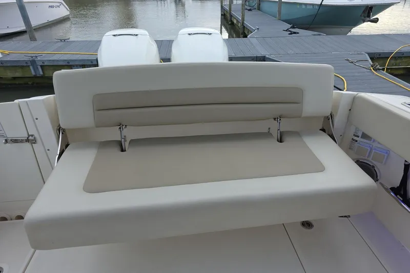 Slide: The Image of 2018 Boston Whaler 320 Vantage boat with cushioned seating at the stern, docked by the water. - 21