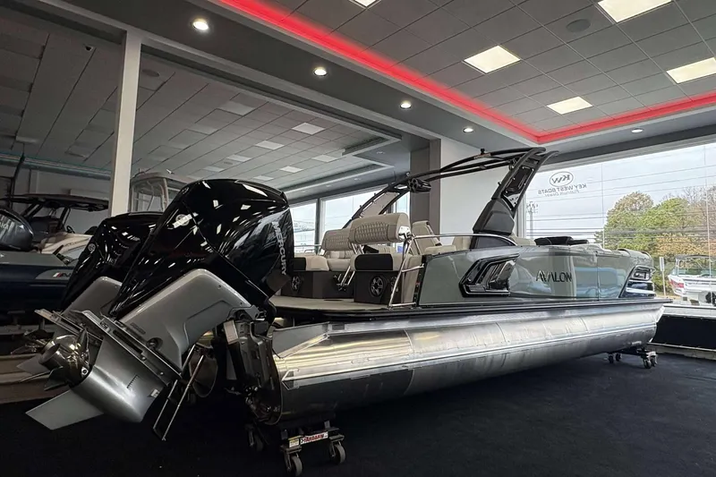 The Image of 2026 Avalon Excalibur 25' pontoon boat displayed indoors with dual Mercury engines. - 0