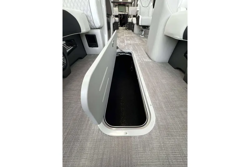 Slide: The Image of 2026 Avalon Excalibur 25' interior storage compartment with open hatch on carpeted floor. - 19