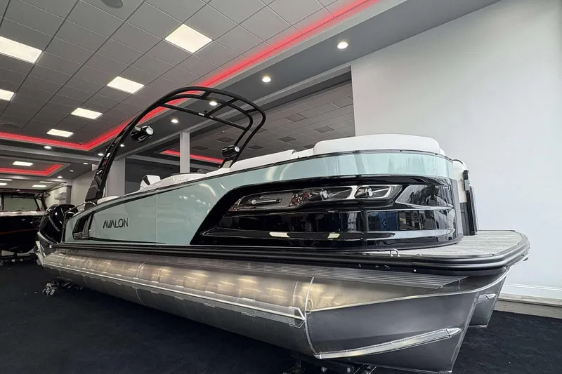 Slide: The Image of 2026 Avalon Excalibur 25' pontoon boat displayed in a showroom with modern lighting. - 2