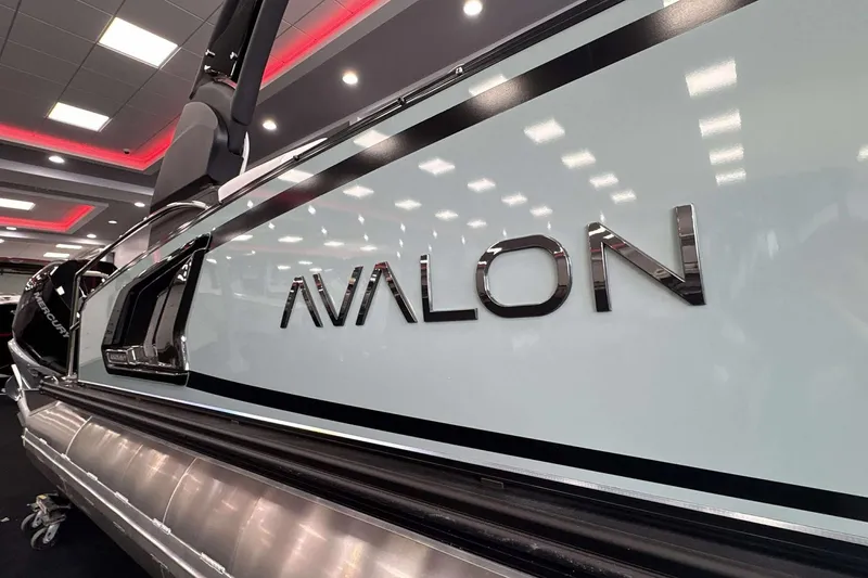 Slide: The Image of 2026 Avalon Excalibur 25' boat showcased indoors with sleek design and branding. - 29