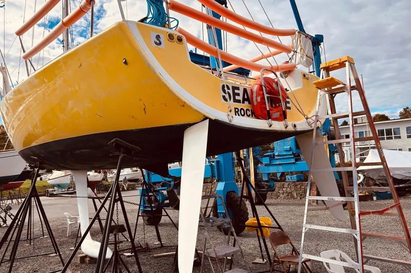 Slide: The Image of Yellow 2003 Beneteau Figaro 2 sailboat on stands, with ladder and equipment nearby. - 5