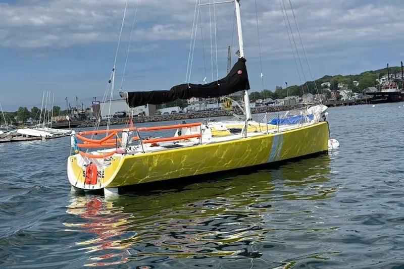 Slide: The Image of Yellow 2003 Beneteau Figaro Beneteau 2 sailboat on calm water, dockside view. - 2