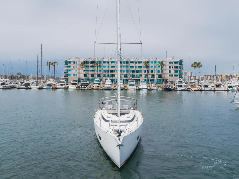 Slide: The Image of 2021 Bavaria C50 Style yacht docked in a marina with modern buildings in the background. - 10