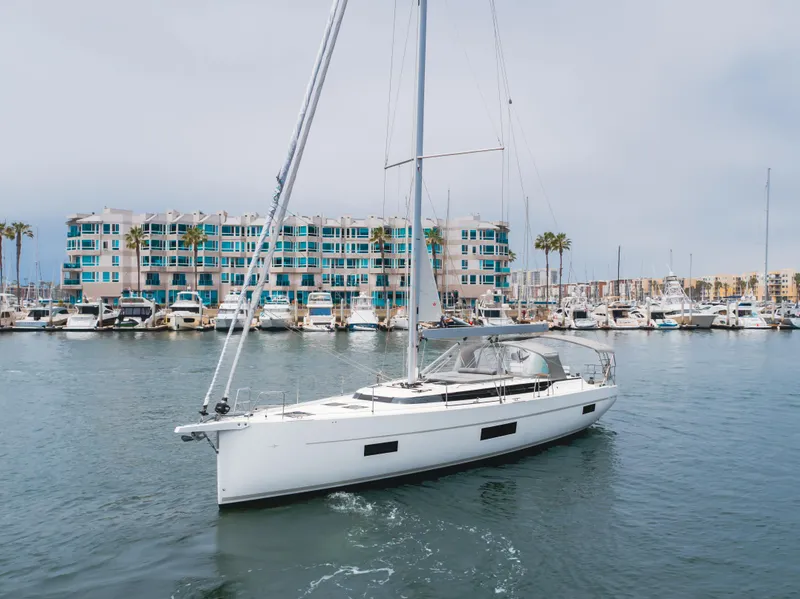 Slide: The Image of 2021 Bavaria C50 Style yacht sailing in a marina with modern buildings in the background. - 11