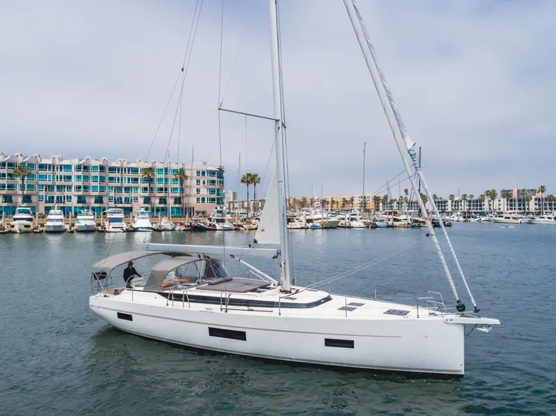 Slide: The Image of 2021 Bavaria C50 Style yacht sailing in a marina with colorful buildings in the background. - 9